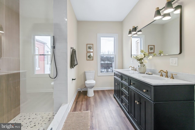 bathroom featuring vanity, tiled shower, hardwood / wood-style floors, and toilet