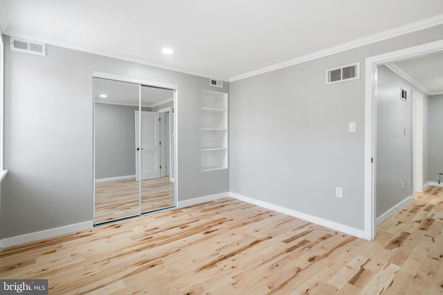 unfurnished bedroom featuring a closet, crown molding, and light wood-type flooring