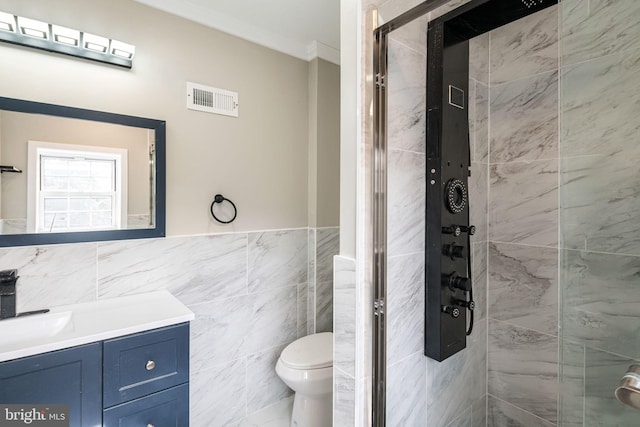 bathroom featuring toilet, tile walls, ornamental molding, vanity, and a shower with door