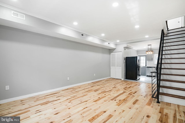 unfurnished living room with ornamental molding and light hardwood / wood-style floors