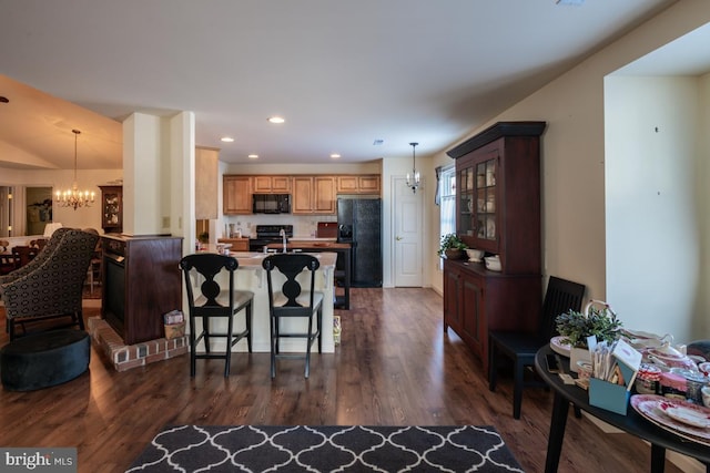 kitchen featuring dark wood-type flooring, black appliances, and a chandelier