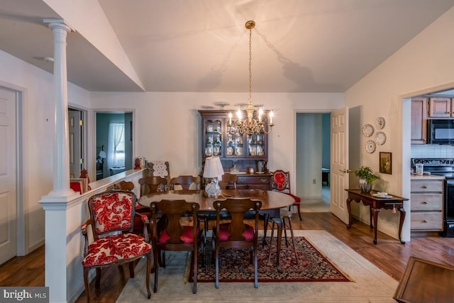 dining area featuring lofted ceiling, hardwood / wood-style floors, and decorative columns