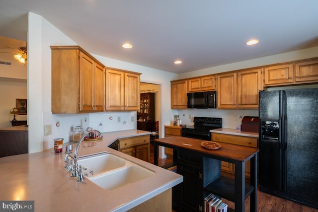 kitchen featuring tasteful backsplash, kitchen peninsula, sink, and black appliances