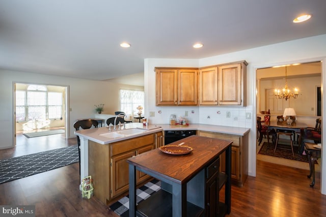 kitchen with dark wood-type flooring, decorative light fixtures, kitchen peninsula, and sink