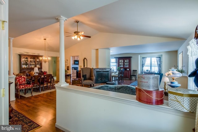 living room featuring lofted ceiling, ceiling fan with notable chandelier, wood-type flooring, and decorative columns