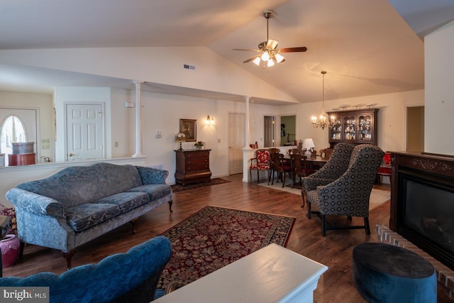 living room with ceiling fan with notable chandelier, lofted ceiling, dark hardwood / wood-style flooring, and decorative columns