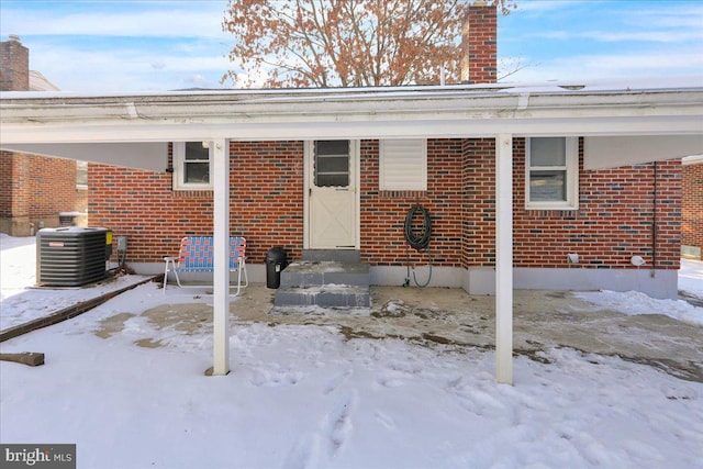 snow covered property entrance featuring cooling unit