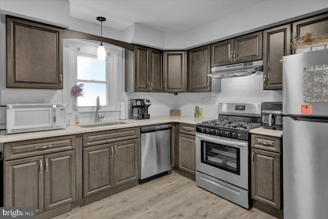 kitchen with appliances with stainless steel finishes, sink, backsplash, dark brown cabinets, and light hardwood / wood-style flooring