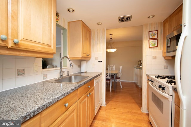 kitchen with sink, decorative backsplash, hanging light fixtures, white appliances, and light hardwood / wood-style flooring