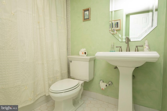 bathroom featuring tile patterned flooring, toilet, and walk in shower