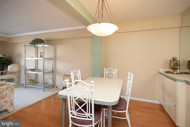 dining area featuring hardwood / wood-style floors, ornamental molding, and beamed ceiling