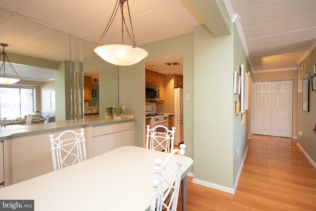 dining room featuring ornamental molding, sink, and light hardwood / wood-style flooring