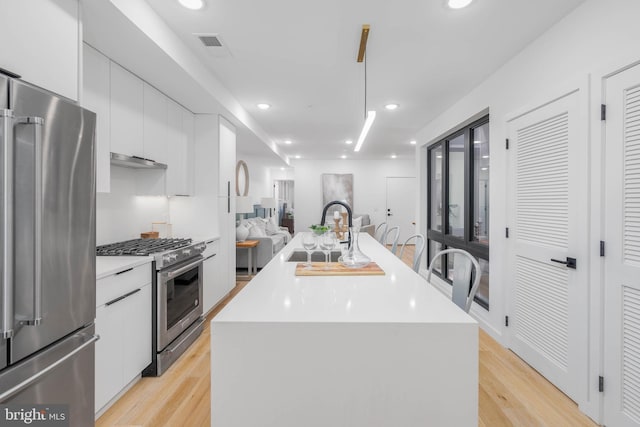 kitchen with white cabinetry, sink, premium appliances, and a kitchen island