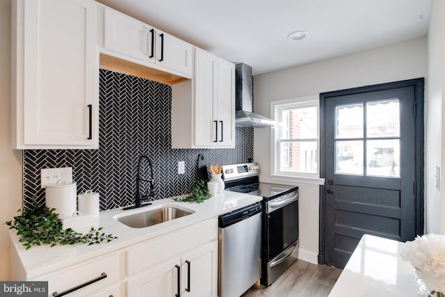 kitchen featuring sink, wall chimney exhaust hood, white cabinets, and appliances with stainless steel finishes