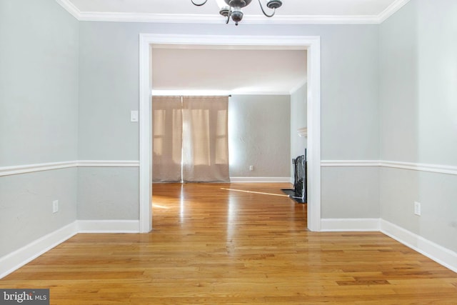 empty room with crown molding, wood-type flooring, and a chandelier