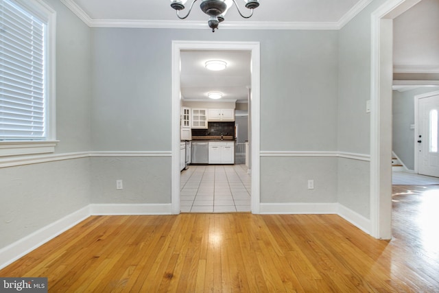 unfurnished dining area with crown molding, a chandelier, and light hardwood / wood-style flooring