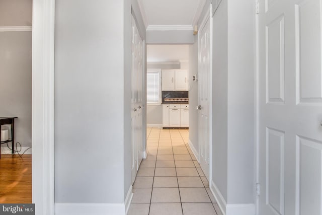 hallway featuring ornamental molding and light tile patterned floors