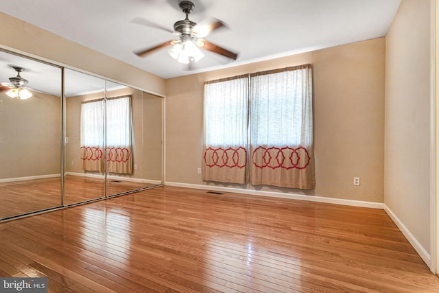 unfurnished bedroom with hardwood / wood-style flooring, a closet, and ceiling fan