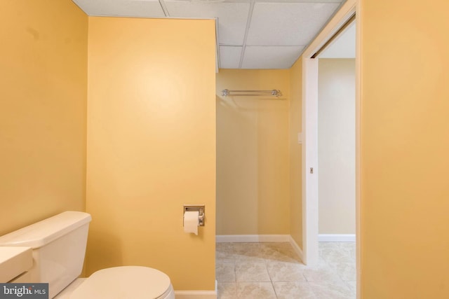 bathroom with tile patterned flooring, a drop ceiling, and toilet