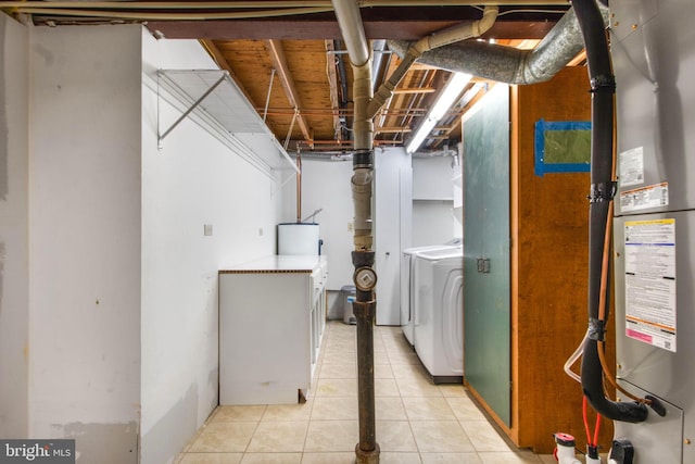 basement with light tile patterned floors, water heater, and washing machine and clothes dryer