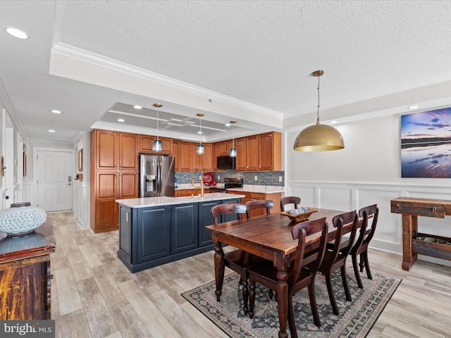 dining room with crown molding, light hardwood / wood-style flooring, and a raised ceiling