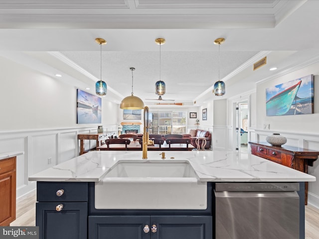 kitchen with light stone countertops, dishwasher, hanging light fixtures, an island with sink, and a tray ceiling