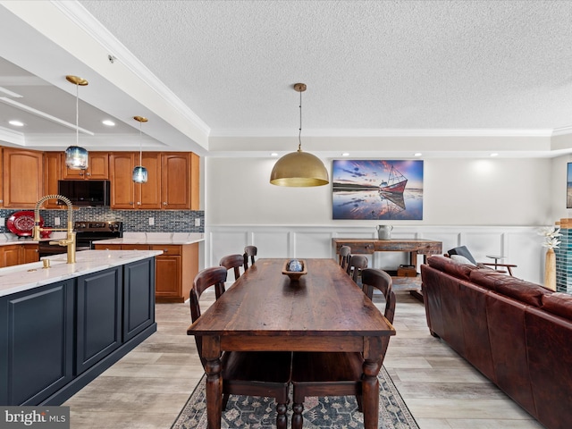 dining area featuring light hardwood / wood-style floors, a textured ceiling, a raised ceiling, and ornamental molding