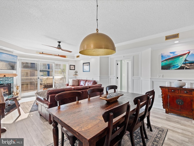 dining room with crown molding, light wood-type flooring, a textured ceiling, and ceiling fan