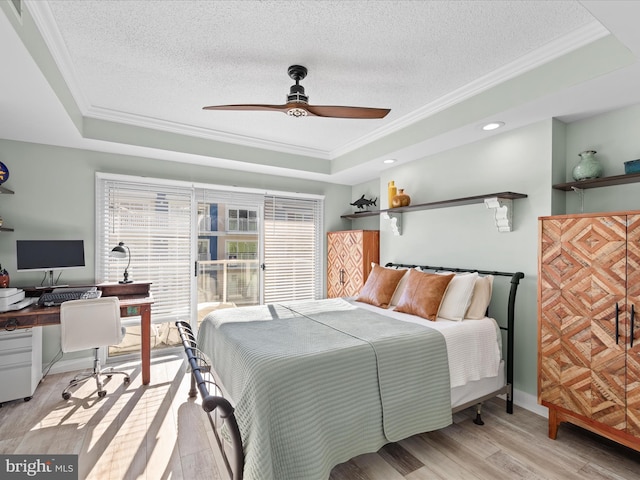 bedroom featuring ceiling fan, a textured ceiling, a tray ceiling, and light hardwood / wood-style flooring