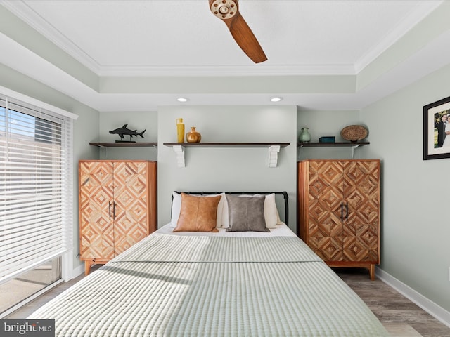 bedroom featuring hardwood / wood-style floors, a tray ceiling, ceiling fan, and ornamental molding