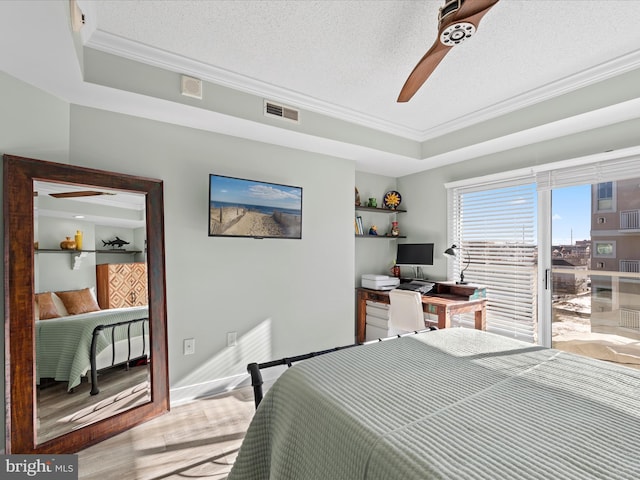 bedroom with a textured ceiling, a tray ceiling, ceiling fan, and ornamental molding