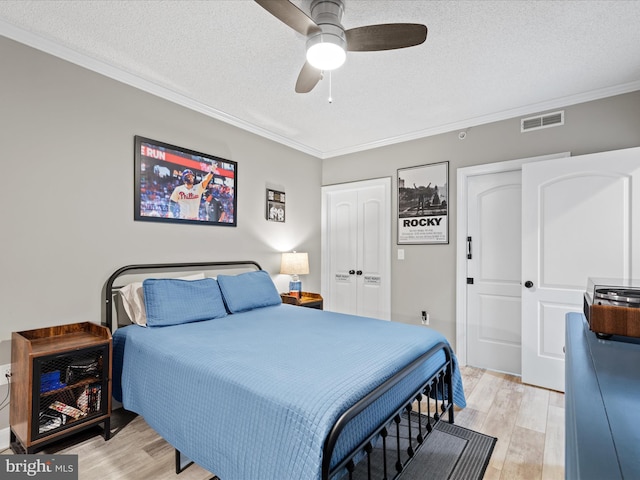 bedroom featuring crown molding, light hardwood / wood-style floors, a textured ceiling, and ceiling fan