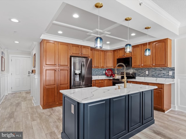 kitchen featuring appliances with stainless steel finishes, decorative light fixtures, coffered ceiling, light stone countertops, and a center island with sink