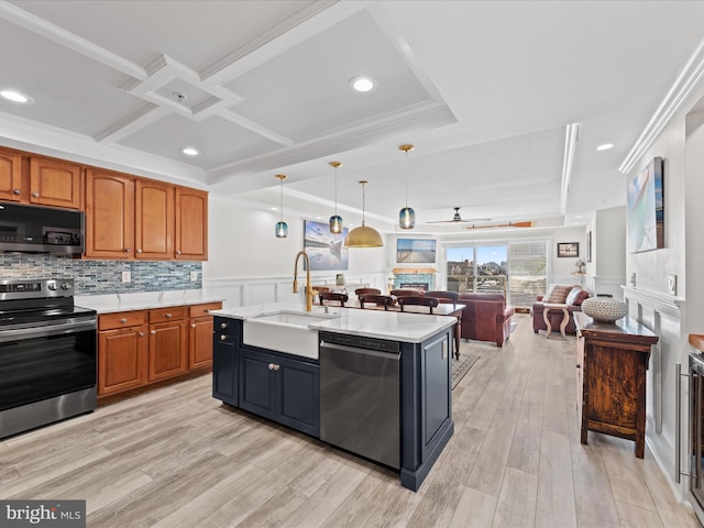 kitchen featuring crown molding, pendant lighting, appliances with stainless steel finishes, sink, and a center island with sink