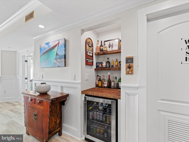 bar with light hardwood / wood-style flooring, wine cooler, butcher block countertops, and ornamental molding