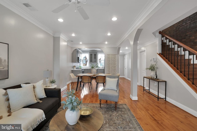 living room featuring crown molding, ceiling fan, and light wood-type flooring