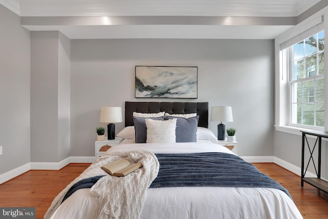 bedroom with hardwood / wood-style flooring, ornamental molding, and multiple windows