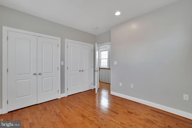 unfurnished bedroom with multiple closets and light hardwood / wood-style floors