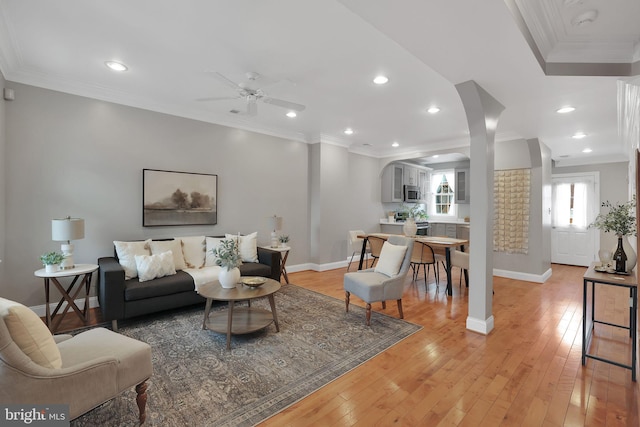 living room with ceiling fan, ornamental molding, and light hardwood / wood-style flooring