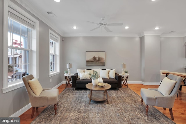 living area with crown molding, ceiling fan, and light wood-type flooring