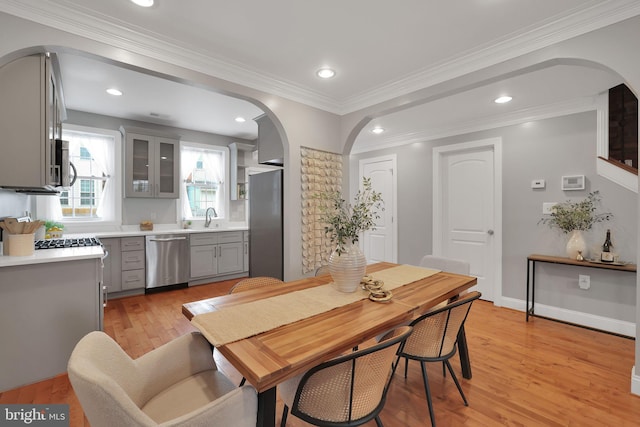 dining space with crown molding, sink, and light hardwood / wood-style floors