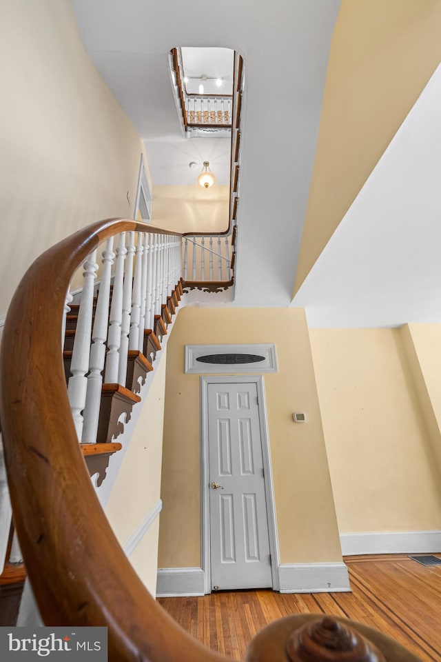 staircase featuring a high ceiling, hardwood / wood-style floors, and baseboards