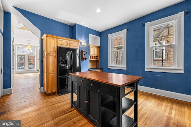 kitchen featuring baseboards, light wood-style flooring, wood counters, black refrigerator with ice dispenser, and dark cabinetry