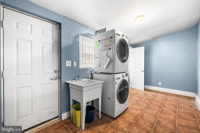 laundry room featuring baseboards, laundry area, tile patterned floors, and stacked washer / drying machine