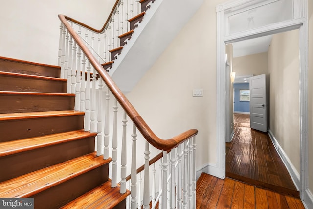 stairway featuring wood-type flooring and baseboards