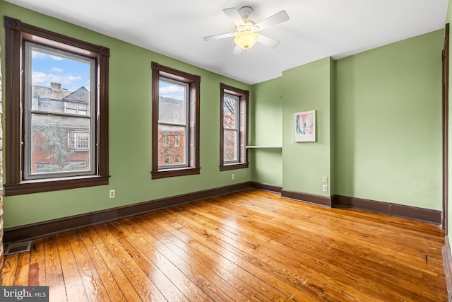 spare room with baseboards, visible vents, hardwood / wood-style floors, and a healthy amount of sunlight