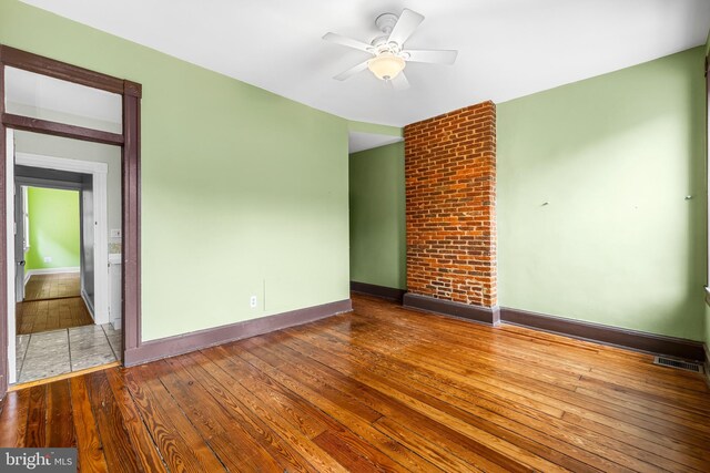 empty room featuring a ceiling fan, wood-type flooring, visible vents, and baseboards