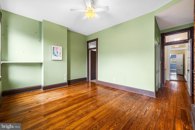 empty room featuring a ceiling fan, baseboards, and hardwood / wood-style floors