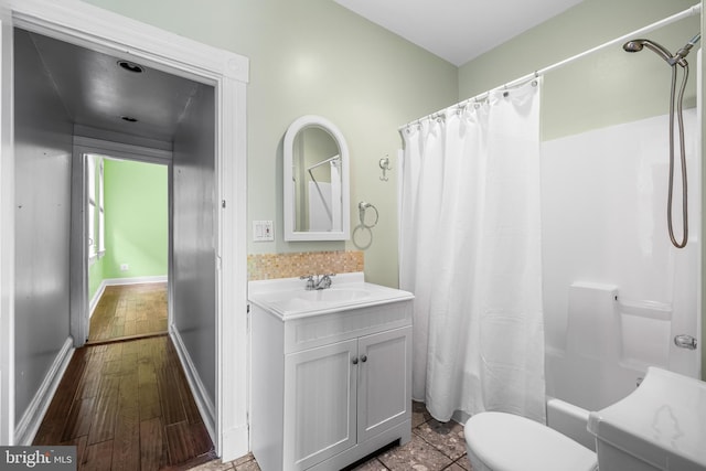 full bath with toilet, wood finished floors, vanity, baseboards, and shower / tub combo with curtain