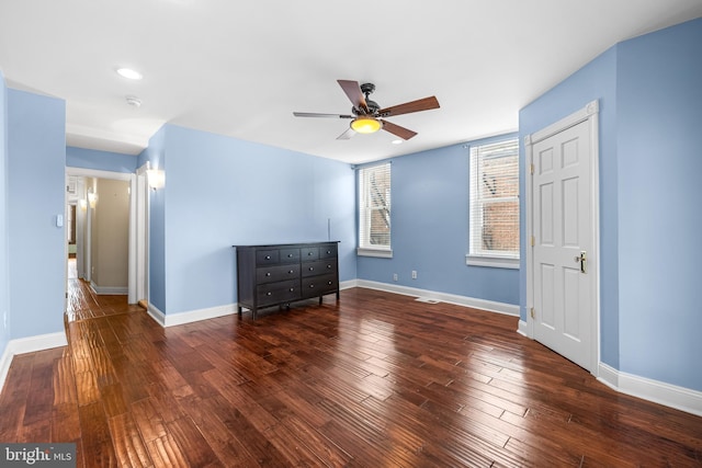 empty room with a ceiling fan, visible vents, baseboards, and wood finished floors